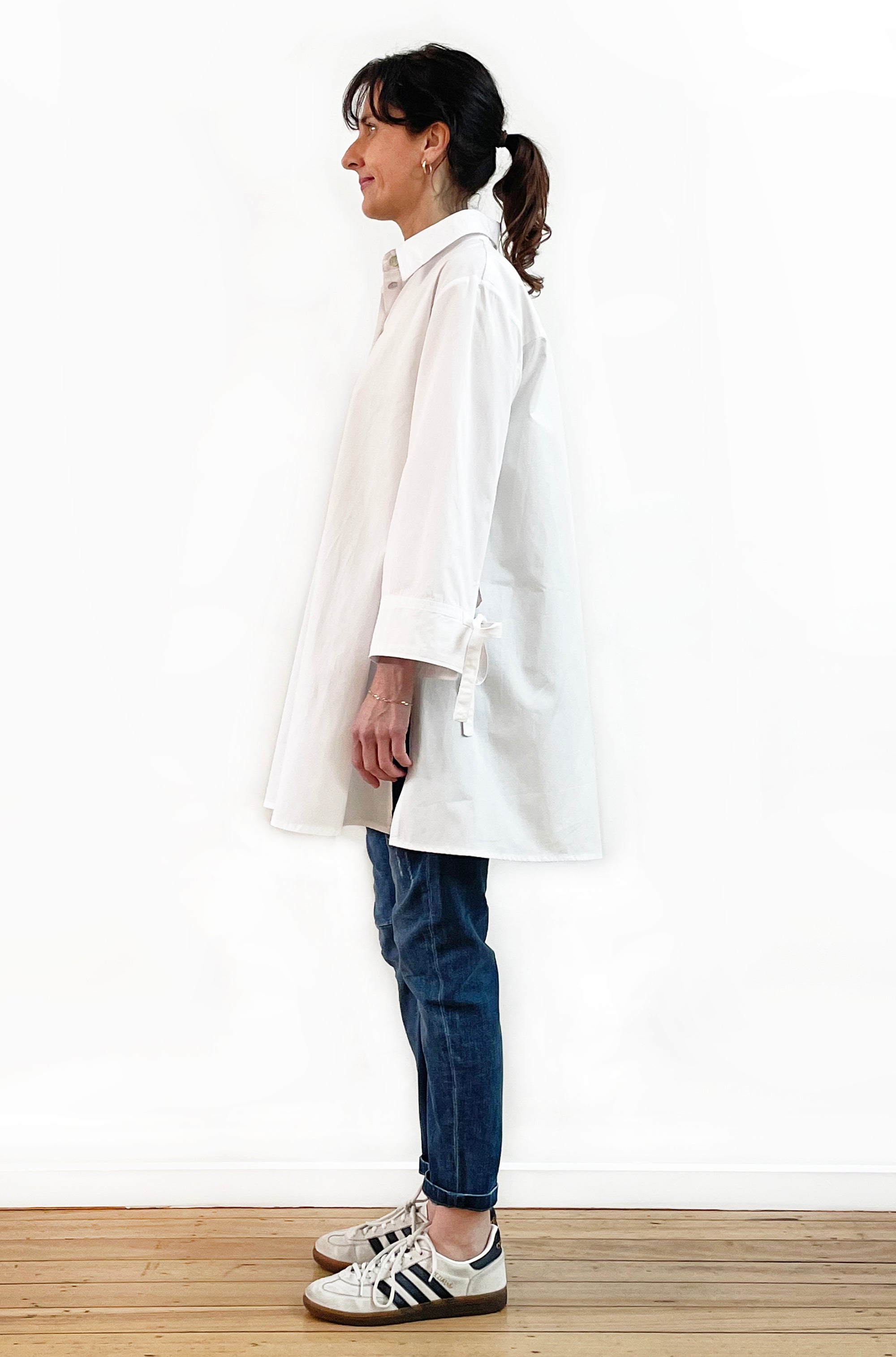 Person wearing a white shirt and blue jeans standing against a white background