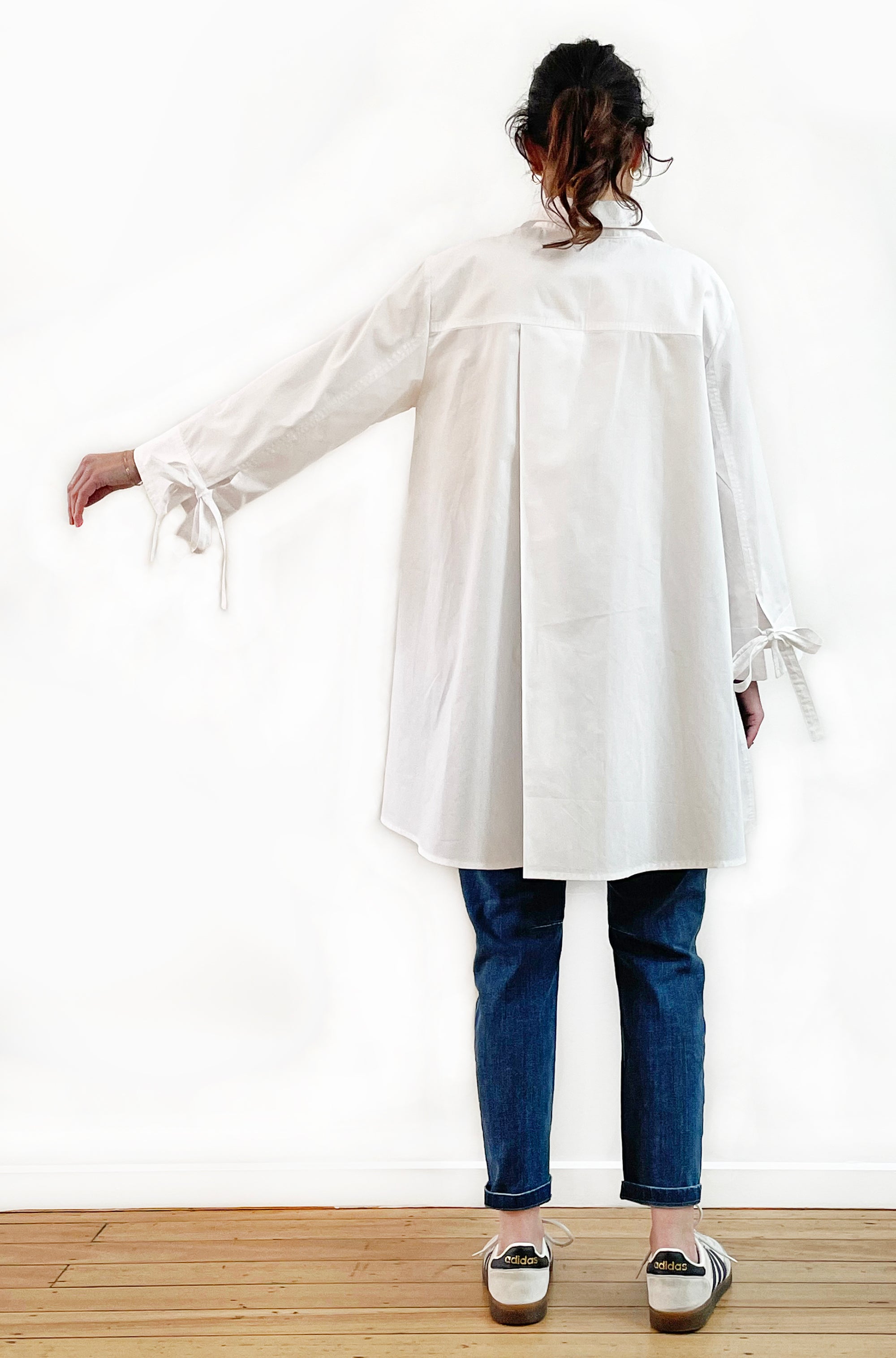 Person wearing a white long-sleeve shirt and blue jeans on a plain background