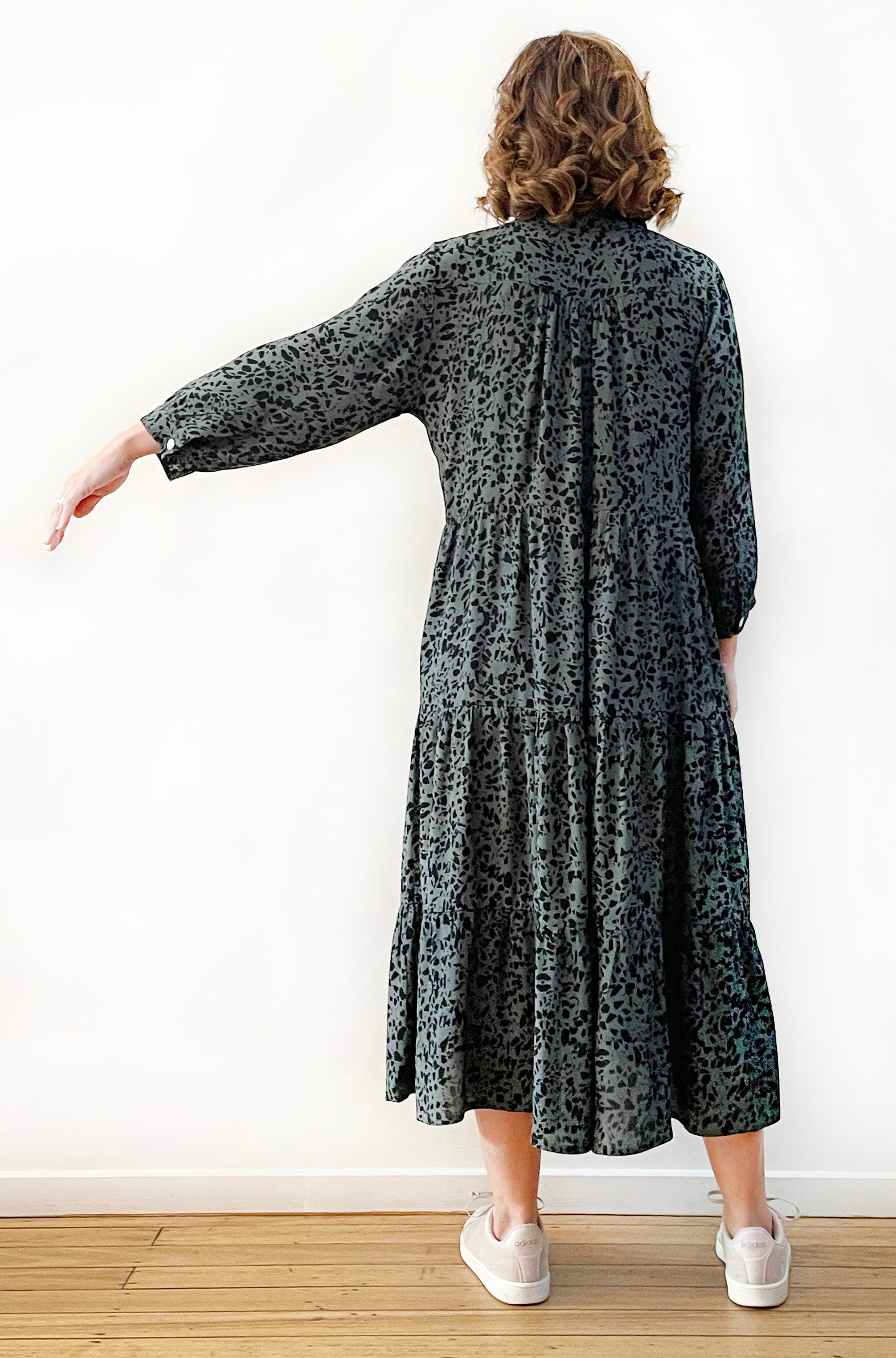 Geelong woman wearing Viscose Tiered Shirt Dress in green leopard print. She is holding her arm out to the side to show the sleeve drop and length